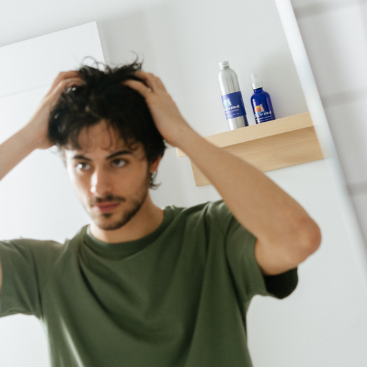 Man using Salty Hair sea salt spray in bathroom mirror