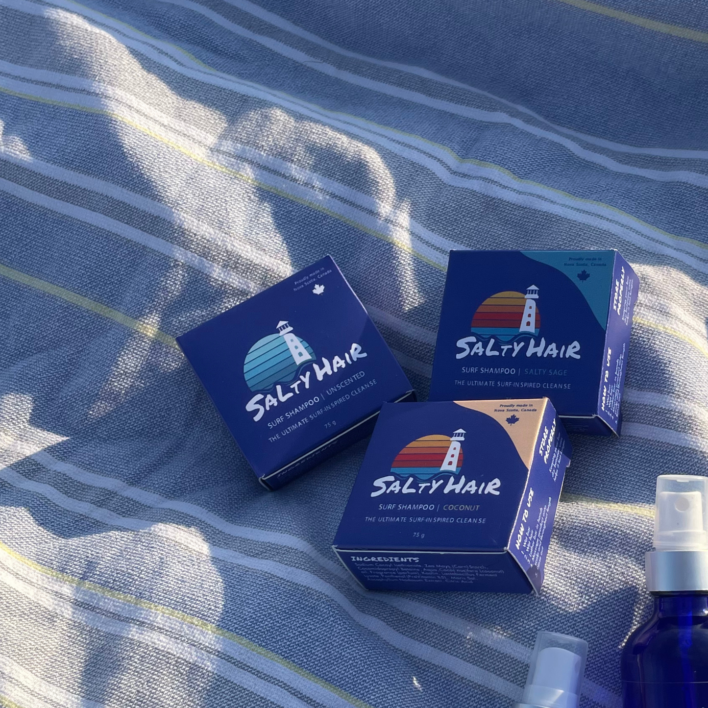 Three 'Salty Hair' surf shampoo product boxes on a blue and white beach towel.